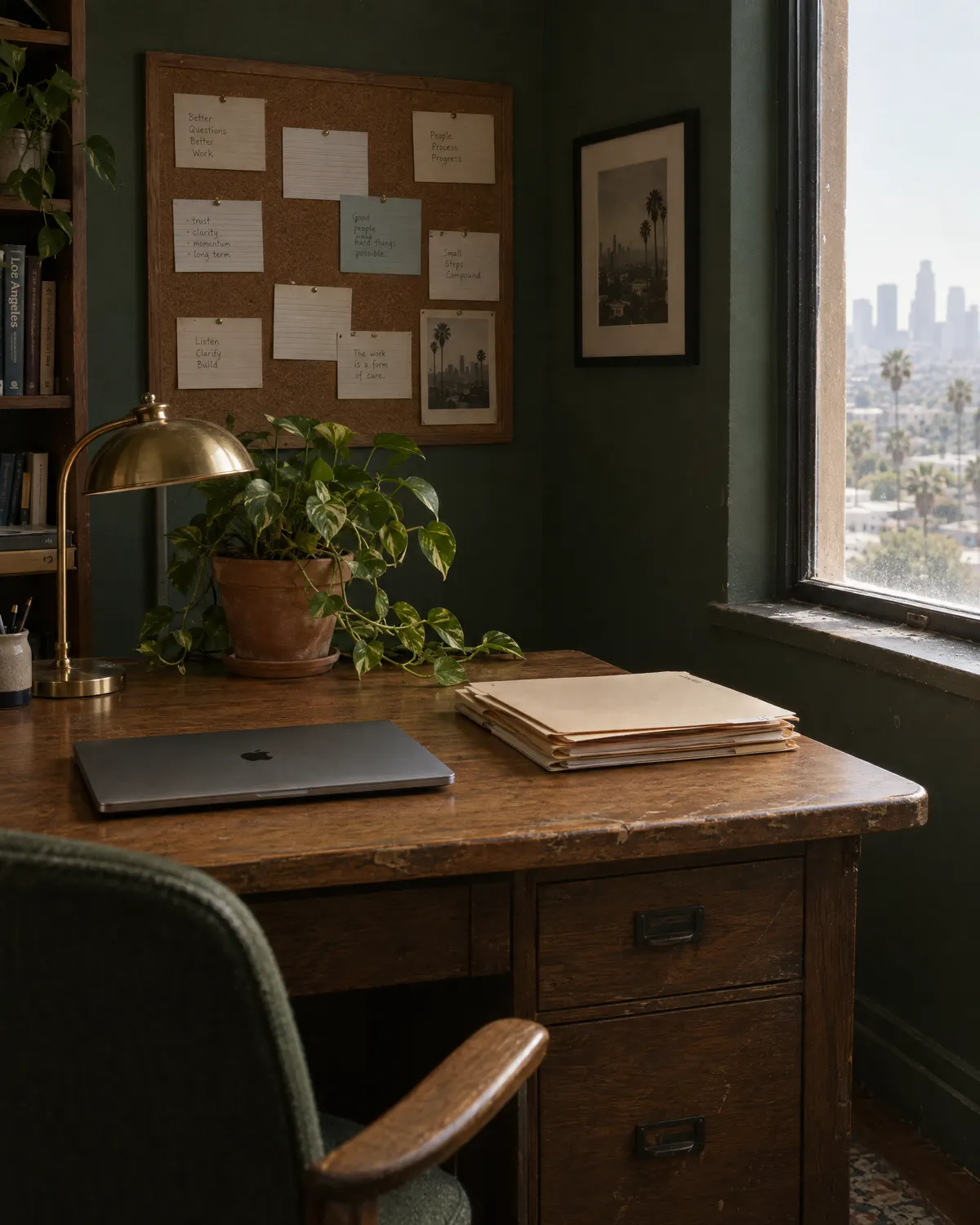 A quiet office corner with an oak desk, folders, a brass lamp and a trailing plant